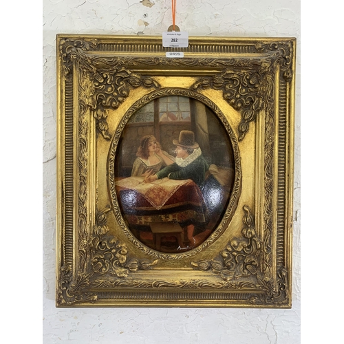 282 - A gilt framed oil on board of a couple signed lower right - approx. 41cm high x 36cm wide