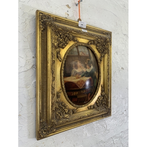 282 - A gilt framed oil on board of a couple signed lower right - approx. 41cm high x 36cm wide