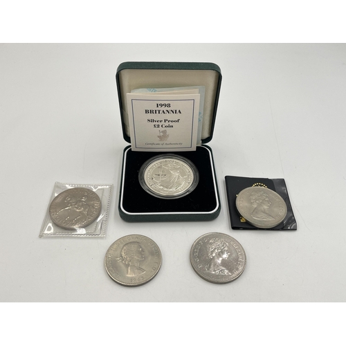 2334 - Five British coins to include cased 95.8% Brittania silver £2 with certificate of authenticity, 1965... 