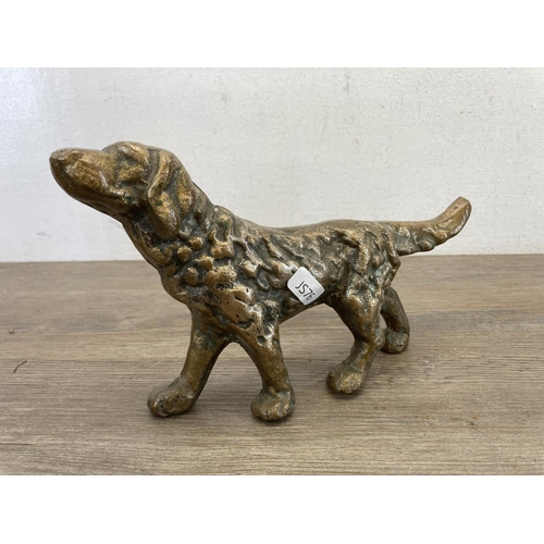 464 - Four pieces of brassware, cast dog figurine, Viking figurine, squirrel ornament and chamberstick