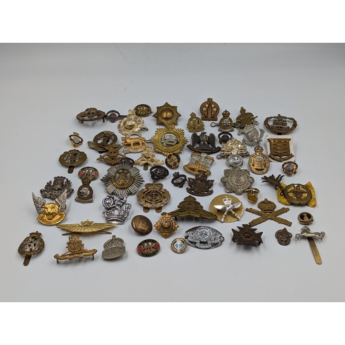 2166 - A large collection of military cap badges