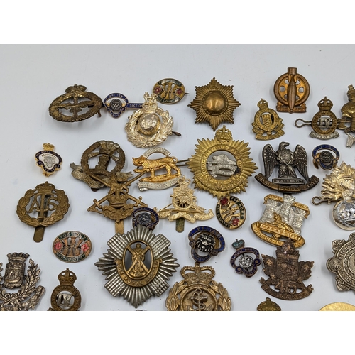 2166 - A large collection of military cap badges