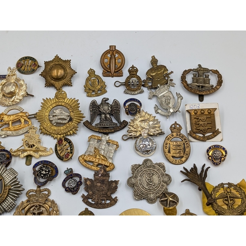 2166 - A large collection of military cap badges