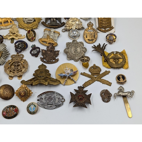 2166 - A large collection of military cap badges