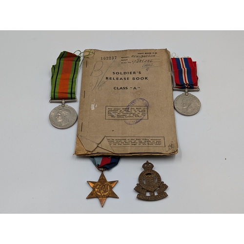 2180 - A WWII British medal trio with soldier's release book and Royal Army Ordnance Corps cap badge