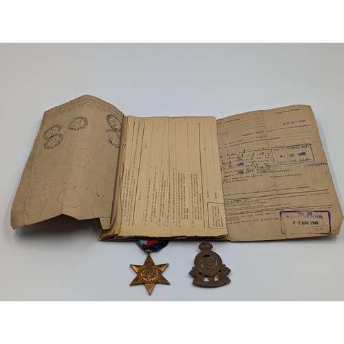 2180 - A WWII British medal trio with soldier's release book and Royal Army Ordnance Corps cap badge