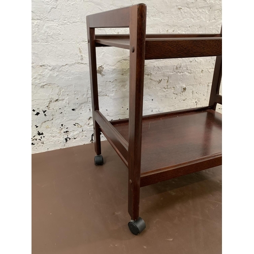113 - A mid 20th century stained teak two tier tea trolley - approx. 64cm high x 45cm wide x 68cm long