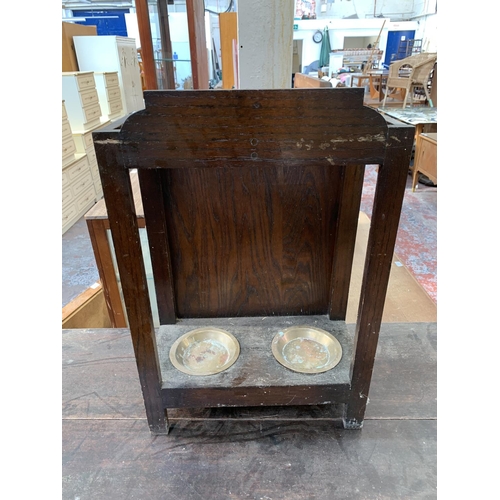 126 - An early 20th century carved oak two section stick stand with two brass circular drip trays - approx... 