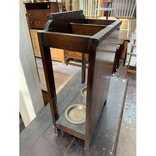 126 - An early 20th century carved oak two section stick stand with two brass circular drip trays - approx... 