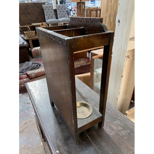 126 - An early 20th century carved oak two section stick stand with two brass circular drip trays - approx... 