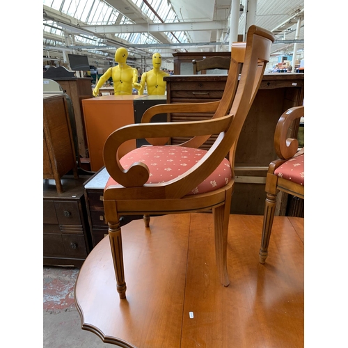 166 - A cherry wood drop leaf pedestal dining table and two carver chairs