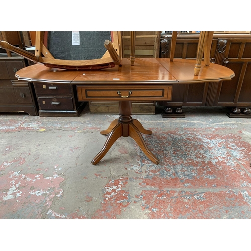 166 - A cherry wood drop leaf pedestal dining table and two carver chairs