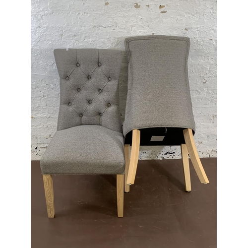 192 - A pair of modern grey button back fabric upholstered dining chairs on oak supports