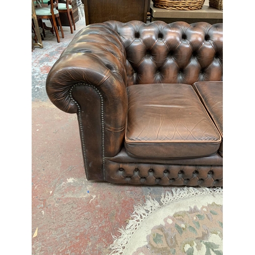 196 - A brown leather Chesterfield three seater sofa - approx. 71cm high x 196cm wide x 94cm deep