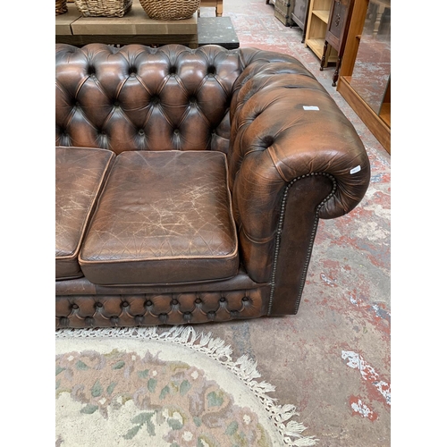 196 - A brown leather Chesterfield three seater sofa - approx. 71cm high x 196cm wide x 94cm deep