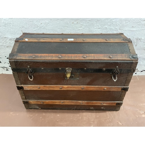 229 - An early 20th century black painted fibreboard and oak banded dome top travel trunk - approx. 55cm h... 