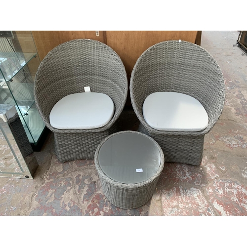 261 - A plastic rattan effect three piece garden furniture set comprising two chairs and one circular glas... 