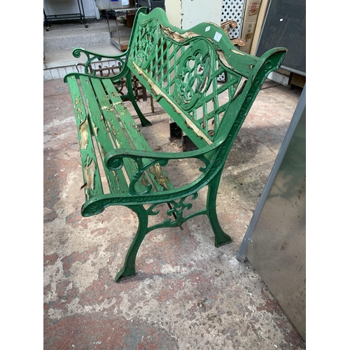 264 - A green painted wooden slatted and cast iron two seater garden bench - approx. 74cm high x 127cm wid... 