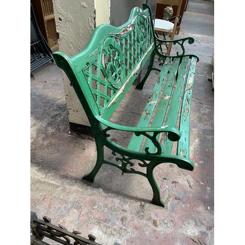 264 - A green painted wooden slatted and cast iron two seater garden bench - approx. 74cm high x 127cm wid... 