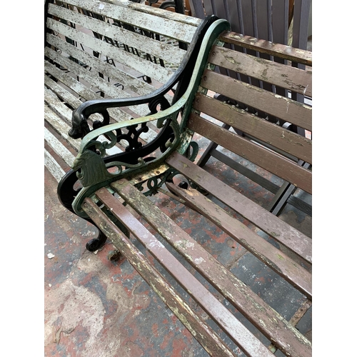 265 - A Victorian style cast iron and wooden slatted two seater garden bench - approx. 77cm high x 128cm w... 