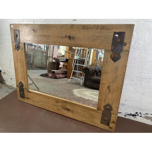 296 - A modern pine framed wall mirror with metal decoration - approx. 122cm high x 162cm wide