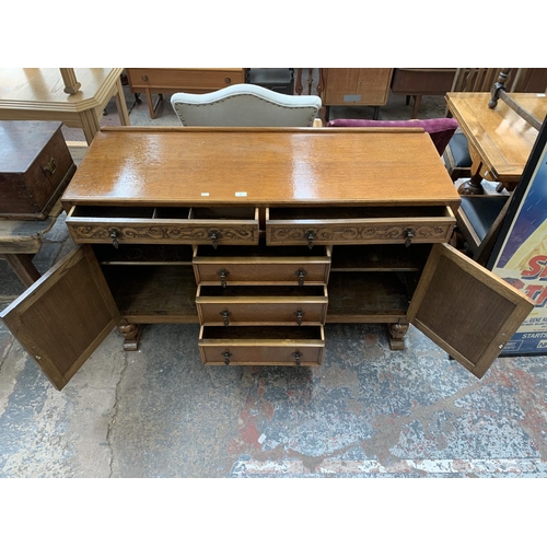 62 - A carved oak sideboard on baluster supports - approx. 88cm high x 134cm wide x 46cm deep