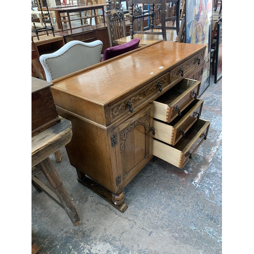 62 - A carved oak sideboard on baluster supports - approx. 88cm high x 134cm wide x 46cm deep