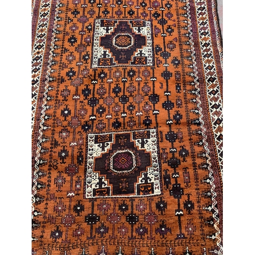 9 - An early/mid 20th century hand knotted orange ground rug - approx. 306cm x 136cm