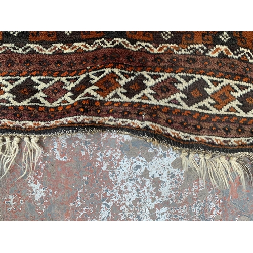 9 - An early/mid 20th century hand knotted orange ground rug - approx. 306cm x 136cm
