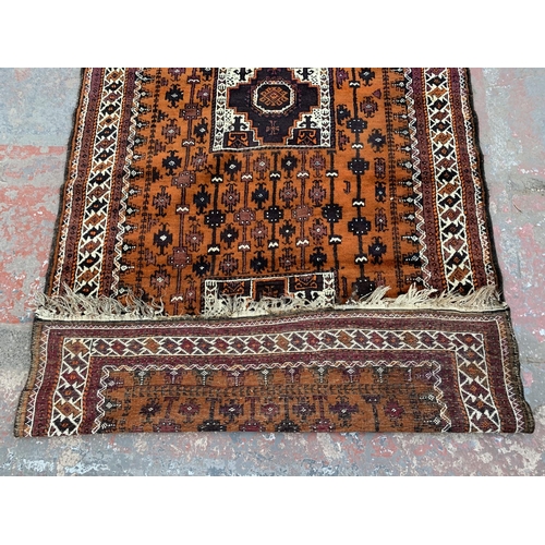 9 - An early/mid 20th century hand knotted orange ground rug - approx. 306cm x 136cm