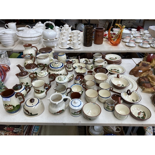 516 - A large collection of Torquay pottery/mottoware to include teapots, water jugs, teacups, serving dis... 