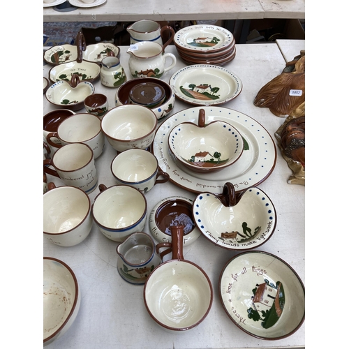 516 - A large collection of Torquay pottery/mottoware to include teapots, water jugs, teacups, serving dis... 