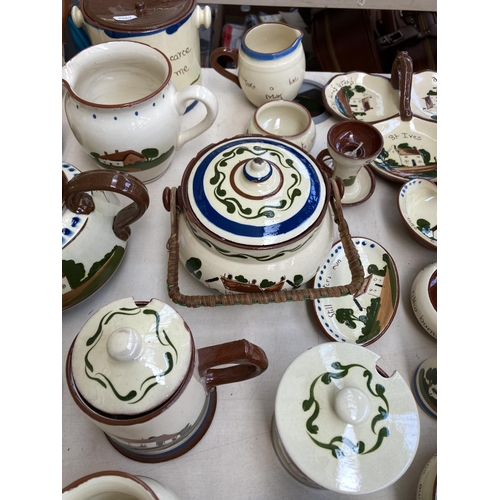 516 - A large collection of Torquay pottery/mottoware to include teapots, water jugs, teacups, serving dis... 