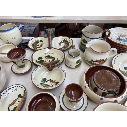 516 - A large collection of Torquay pottery/mottoware to include teapots, water jugs, teacups, serving dis... 