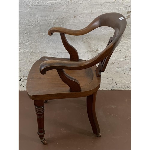 197 - A 19th century mahogany desk chair with carved fretwork back and turned supports on castors - approx... 
