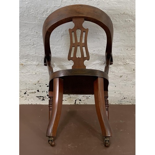 197 - A 19th century mahogany desk chair with carved fretwork back and turned supports on castors - approx... 
