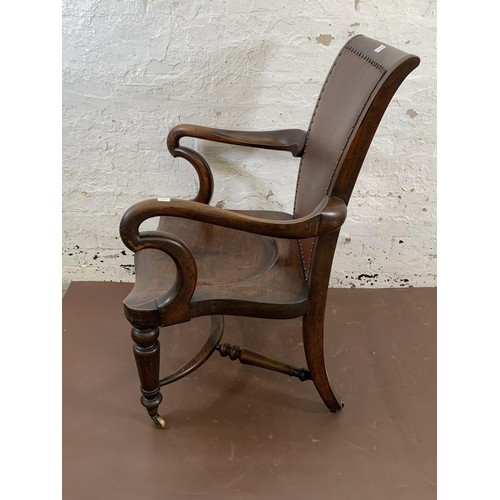 199 - A 19th century Holland & Sons mahogany and studded brown leather library chair with turned supports,... 