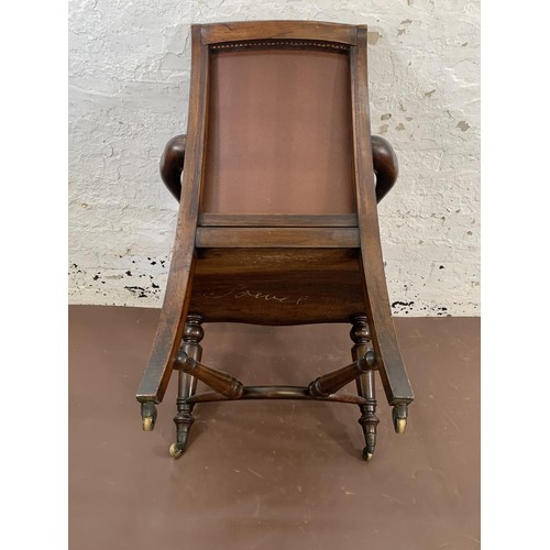 199 - A 19th century Holland & Sons mahogany and studded brown leather library chair with turned supports,... 