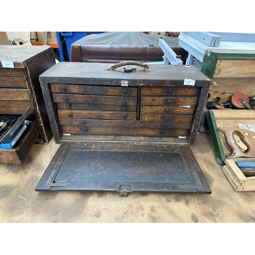 1052 - An early 20th century oak engineer's tool cabinet containing various tap and die sets, spanners etc.