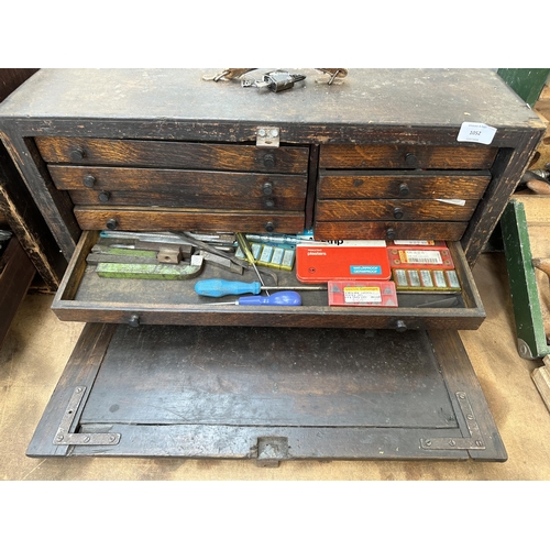 1052 - An early 20th century oak engineer's tool cabinet containing various tap and die sets, spanners etc.