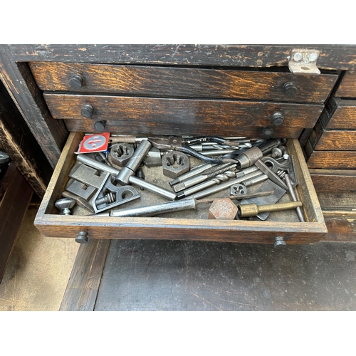 1052 - An early 20th century oak engineer's tool cabinet containing various tap and die sets, spanners etc.