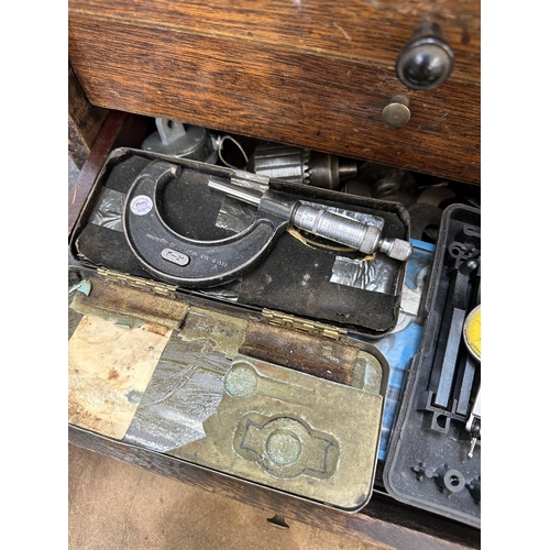 1053 - An early 20th century oak engineer's tool cabinet containing Moore & Wright callipers, tap and die s... 