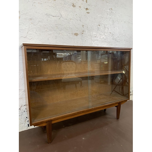 125 - A mid 20th century teak bookcase with two sliding glazed doors - approx. 85cm high x 116cm wide x 27... 