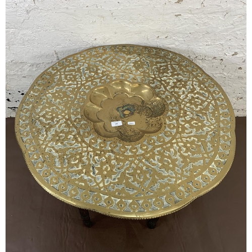 130 - A Middle Eastern carved hardwood and embossed brass travel table - approx. 55cm high x 78cm diameter