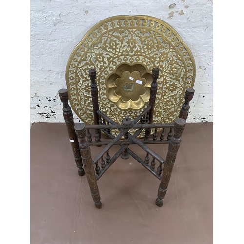 130 - A Middle Eastern carved hardwood and embossed brass travel table - approx. 55cm high x 78cm diameter