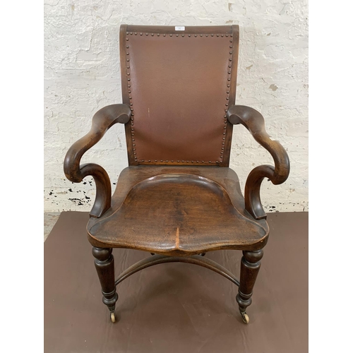 132 - A 19th century Holland & Sons mahogany and studded brown leather library chair with turned supports,... 