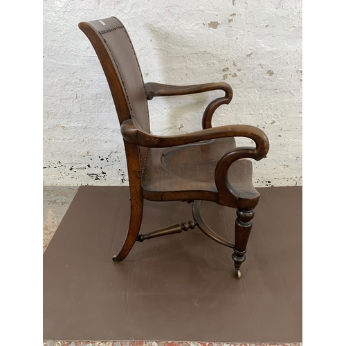 132 - A 19th century Holland & Sons mahogany and studded brown leather library chair with turned supports,... 