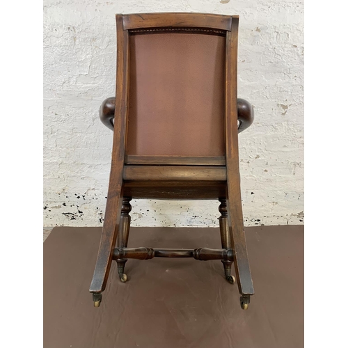 132 - A 19th century Holland & Sons mahogany and studded brown leather library chair with turned supports,... 