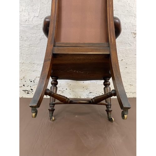 132 - A 19th century Holland & Sons mahogany and studded brown leather library chair with turned supports,... 