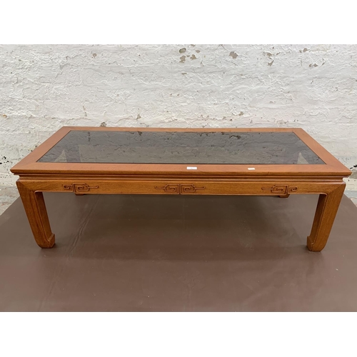 47 - A Chinese carved hardwood and smoked glass rectangular coffee table - approx. 40cm high x 127cm long... 